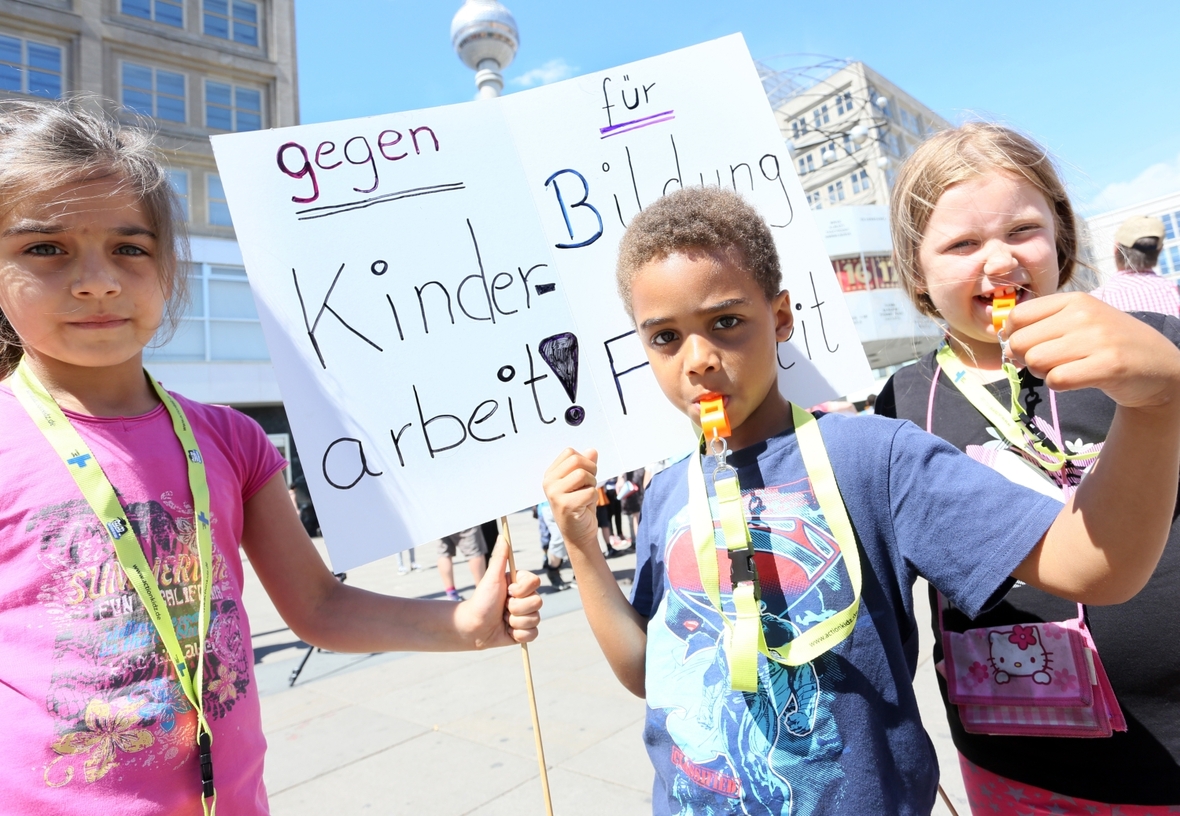 Kinder nehmen in Berlin an einer Aktion gegen Kinderarbeit teil. Auf ihrem Plakat steht "Gegen Kinderarbeit! Für Bildung und Freizeit".