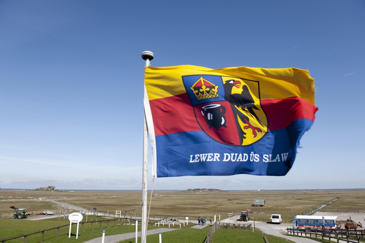 Die nordfriesische Fahne mit Emblem trägt den Wahlspruch "Lewer duad üs slaw", Lieber tot als Sklave. 