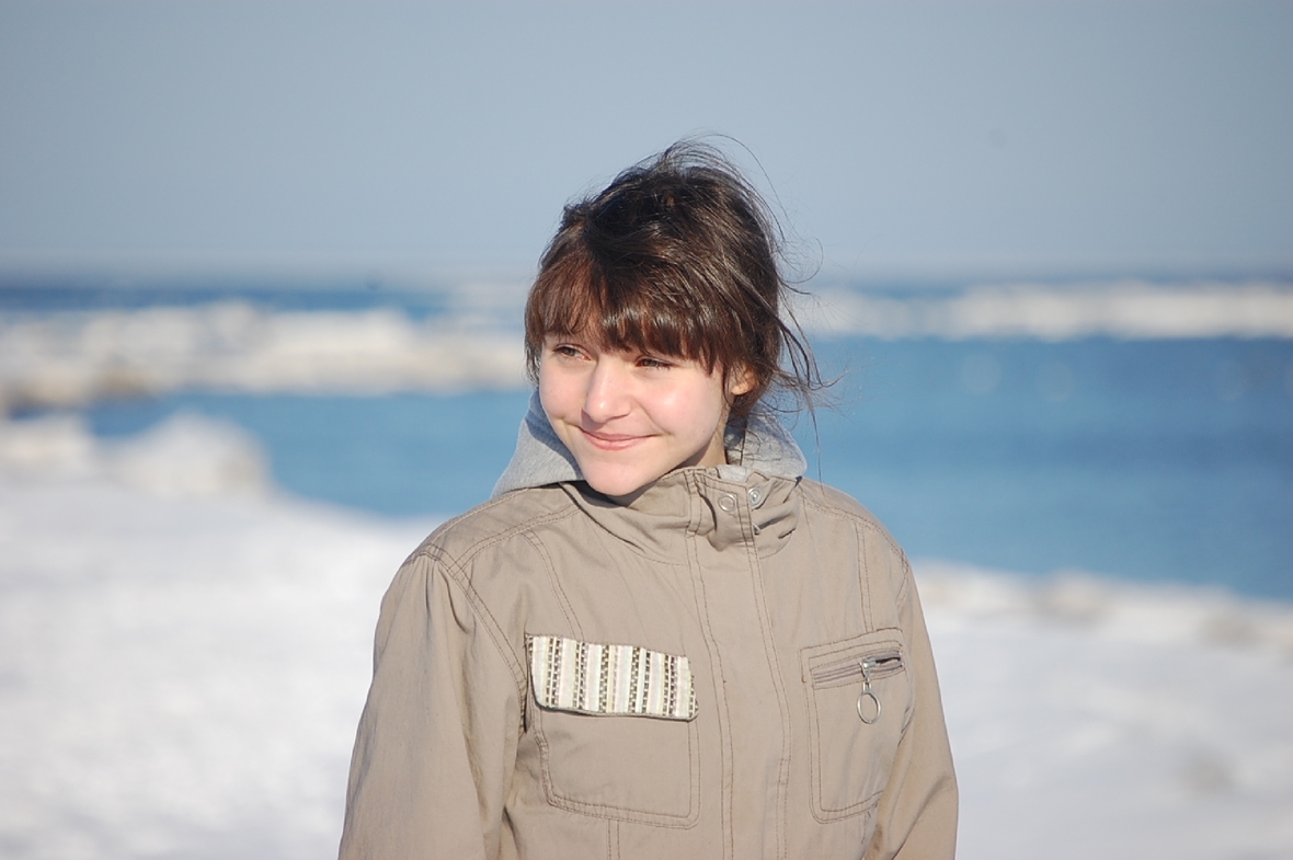Szenenbild: Das Mädchen Kattaka lächelt. Hinter ihr ist das Meer zu sehen.  