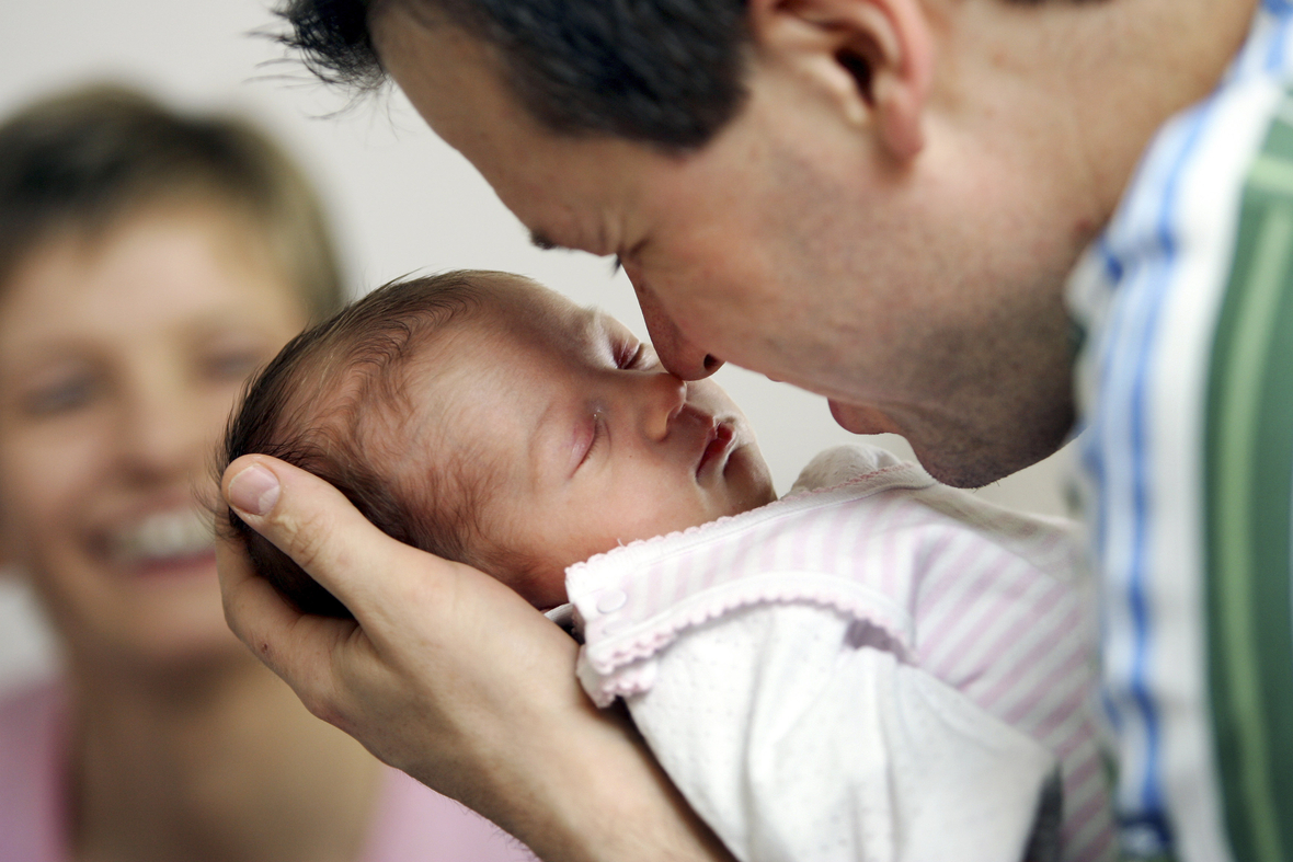 Der Vater hält glücklich sein kleines Baby ganz nah bei sich. Die Familie erhält nun Elterngeld.