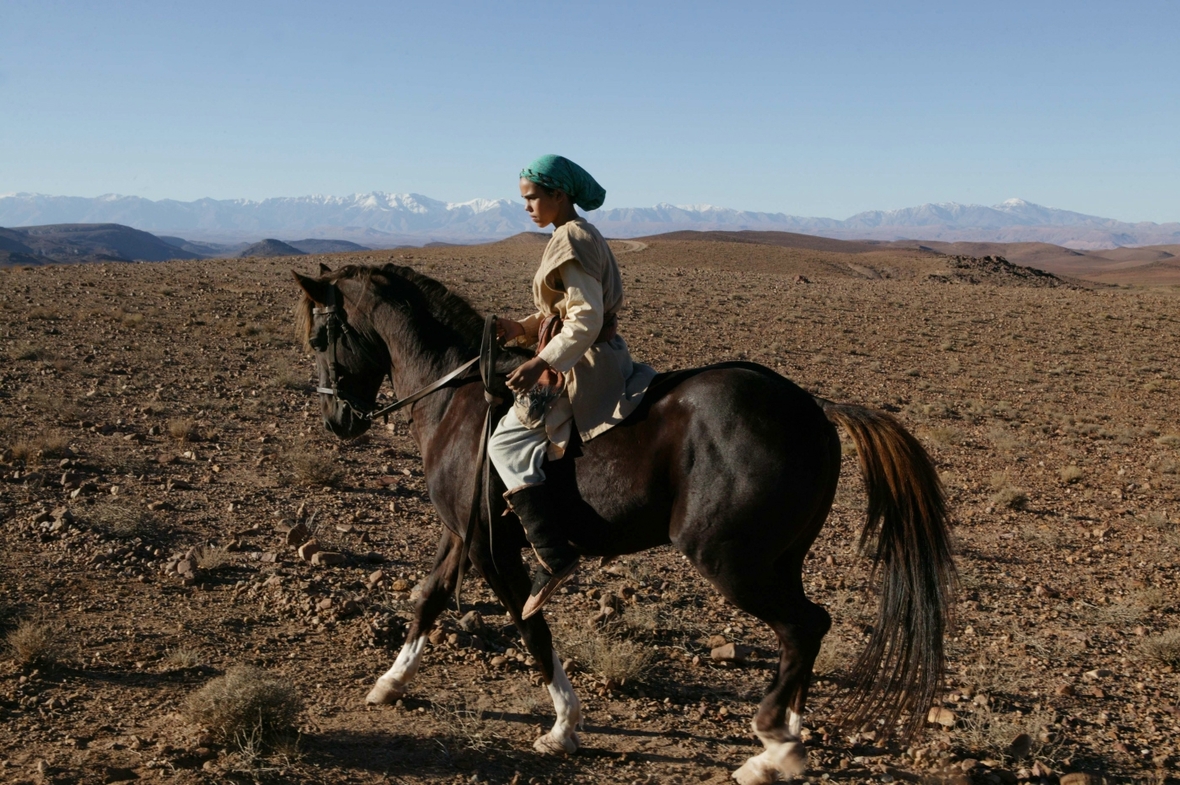 Szenenbild: Das Mädchen Zaina reitet in einer steinigen Gebirgslandschaft auf dem Pferd Zingal.
