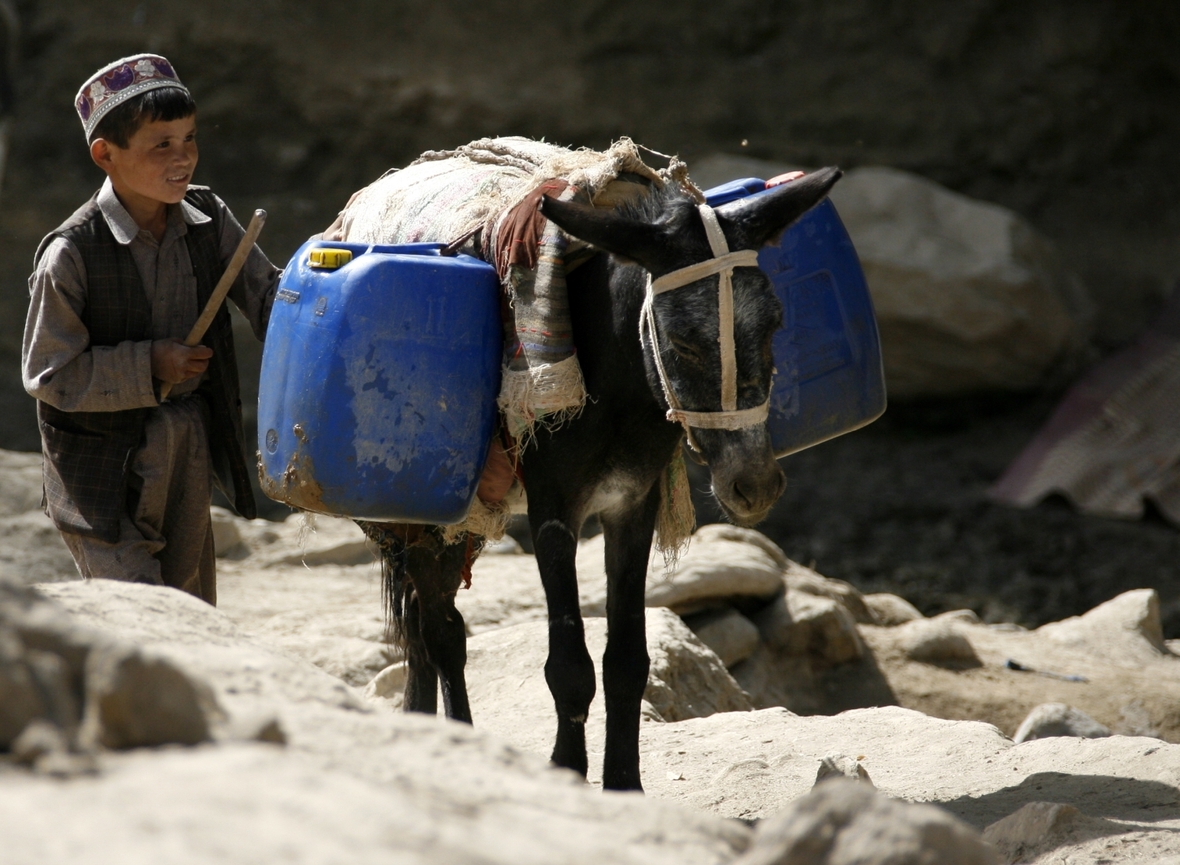 Ein afghanischer Junge treibt in Faisabad, Afghanistan, seinen Esel an. Das Tier ist mit Wasserkanistern beladen.