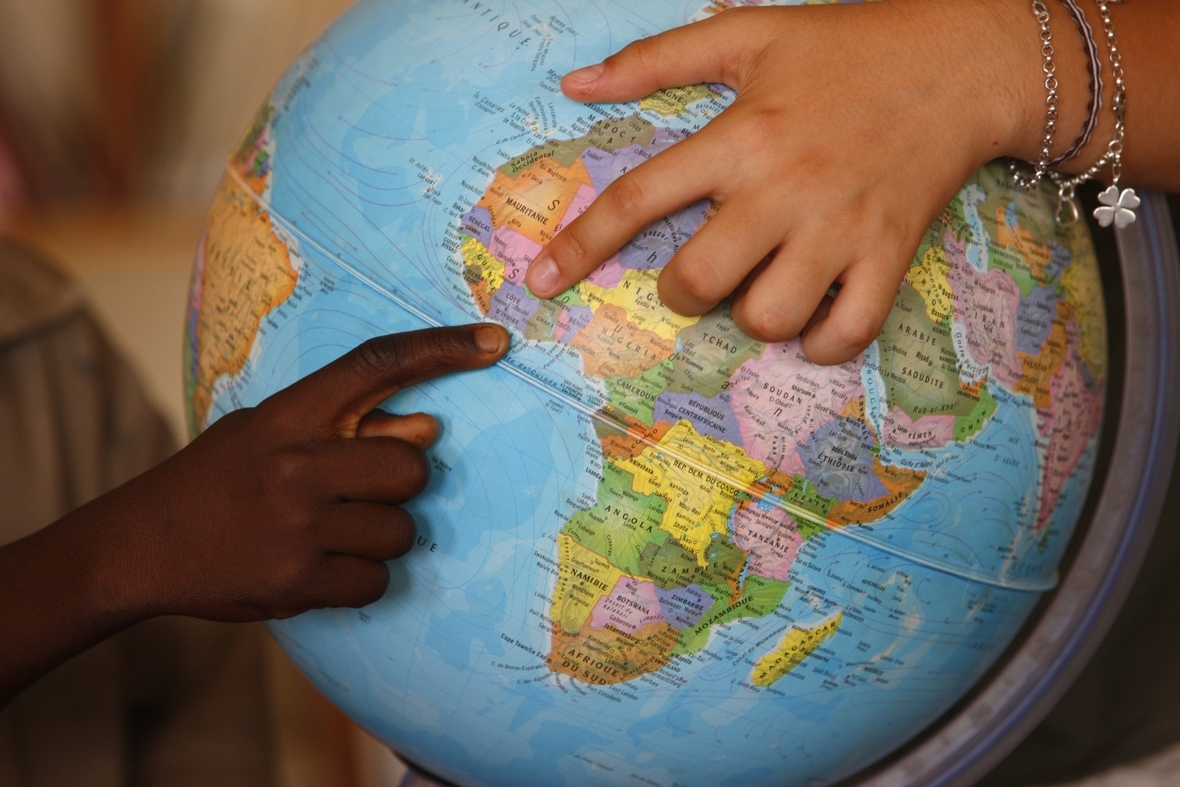 Kinder entdecken auf einem Globus verschiedene Länder