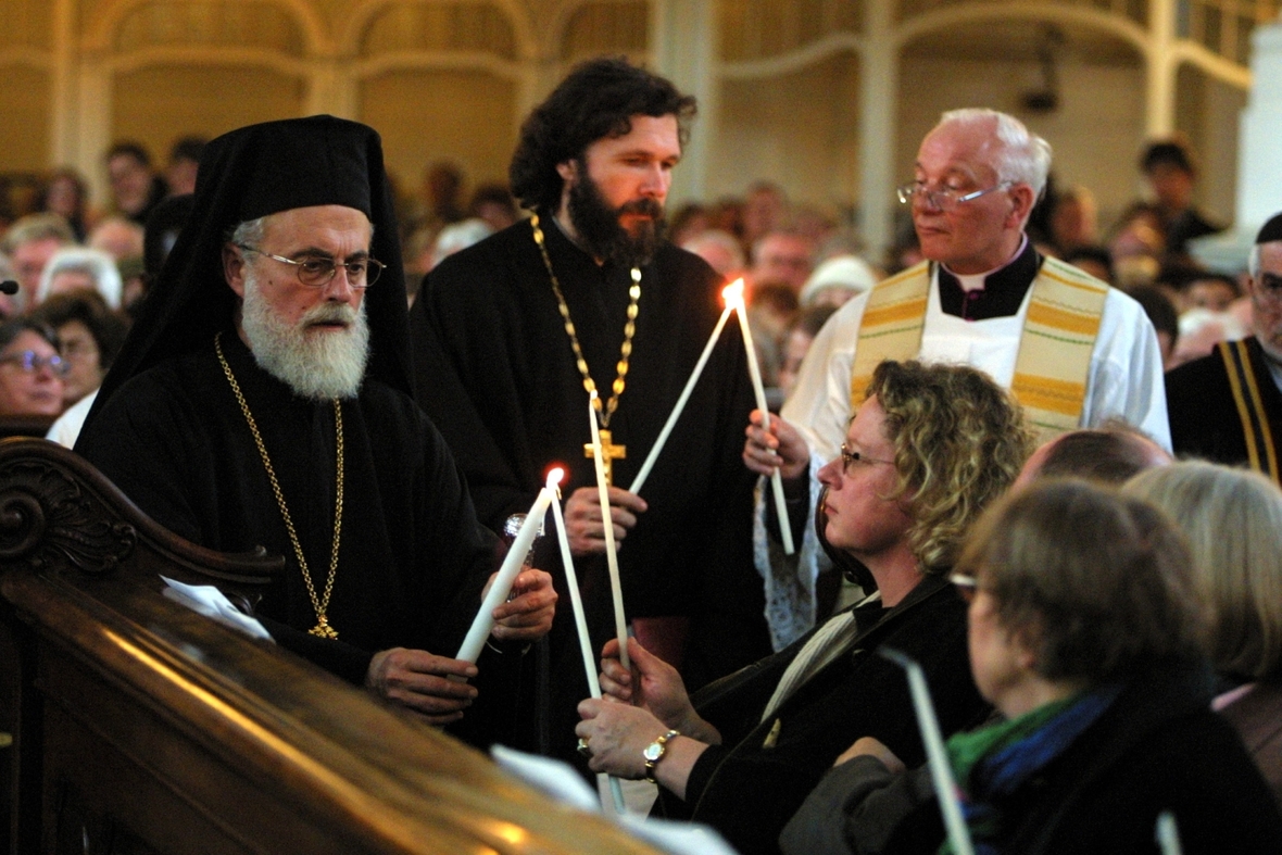 Ein Ostergottesdienst wird hier mit Vertretern verschiedener christlicher Kirchen gefeiert. Der Bischof der griechisch-orthodoxen Gemeinde steht im Fokus des Bildes.
