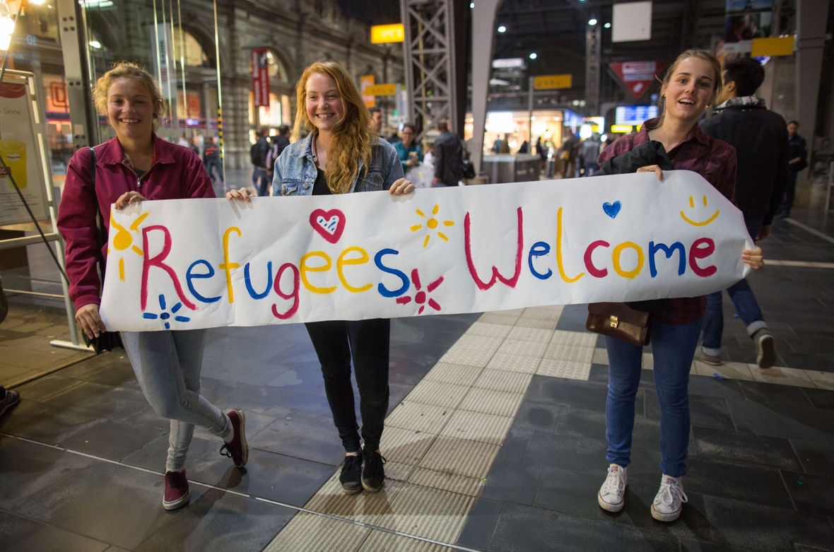 Teenager in Frankfurt am Main begrüßen die Flüchtlinge am Bahnhof mit dem Plakat "Flüchtlinge willkommen".