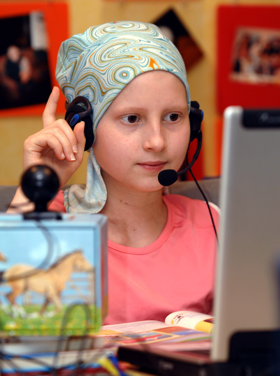 Mädchen mit Kopfhörern und Mikrofon vor einem Laptop für Online-Unterricht. 