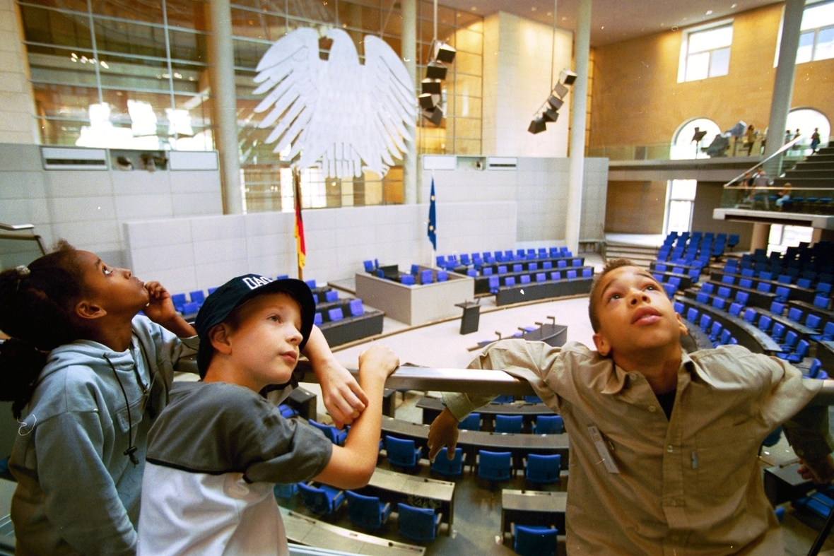 Drei  Schüler schauen sich das Reichstagsgebäude ganz genau an. Das Reichstagsgebäude  ist der Sitz des Deutschen Bundestages.