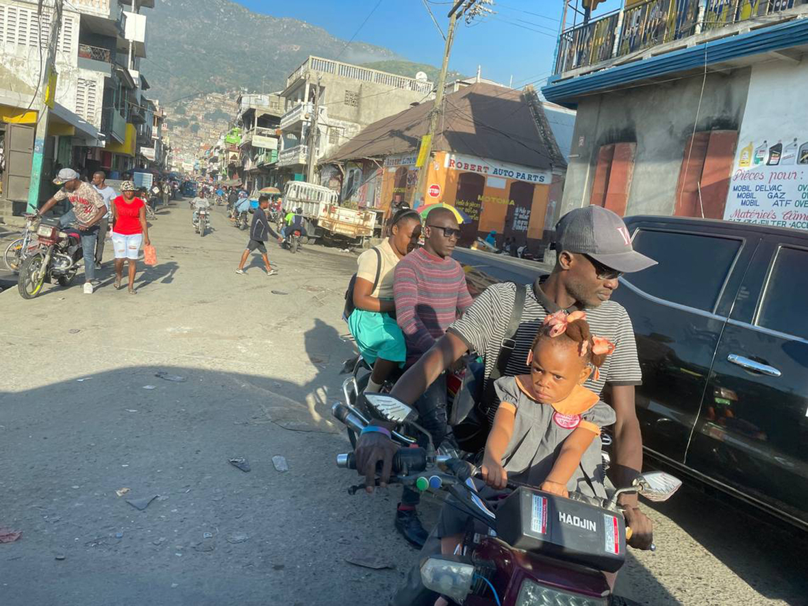 In der Hafenstadt Cap-Haïtien wird ein Mädchen auf einem Moped zur Schule gefahren.