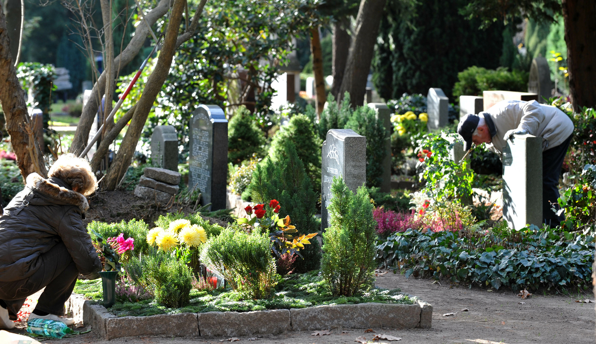 Angehörige pflegen am Totensonntag in Dresden Gräber und gedenken der Verstorbenen. Das Foto zeigt Menschen auf einem Friedhof, die sich um Gräber kümmern.