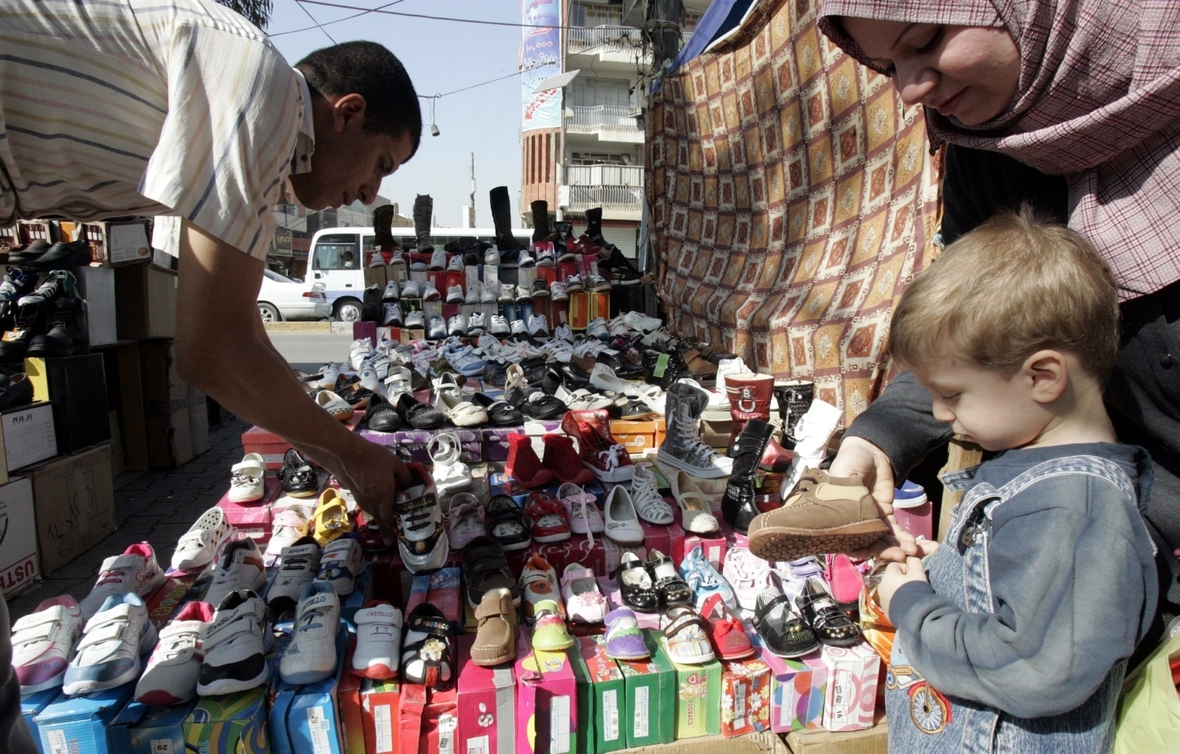 Menschen kaufen an einem Marktstand Schuhe und Kleidung, um sich für das muslimische Opferfest vorzubereiten.


