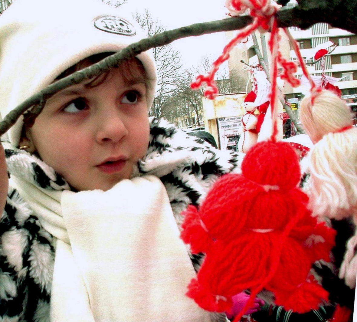 Ein bulgarisches Mädchen betrachtet die Martenizi, ein kleines Püppchen aus roten und weißen Wollfäden