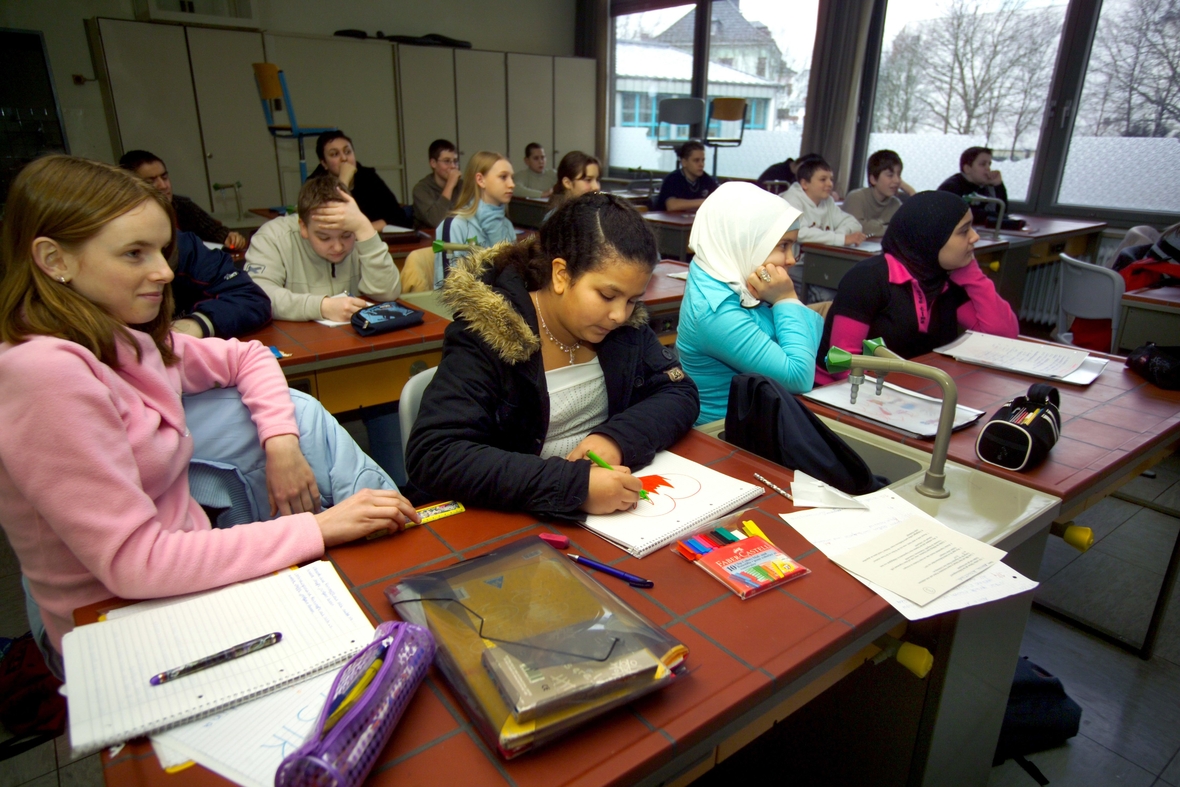 Muslimische Schülerinnen mit und ohne Kopftuch lernen gemeinsam in einer Schulklasse im Ruhrgebiet