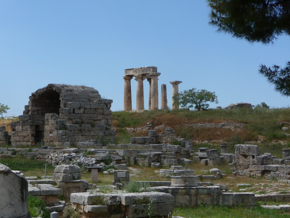 Zu Sehen ist de archäologische Ausgrabungsstätte des antiken Korinth auf der Halbinsel Peloponnes in Griechenland. Im Hintergrund steht der Apollon-Tempel.