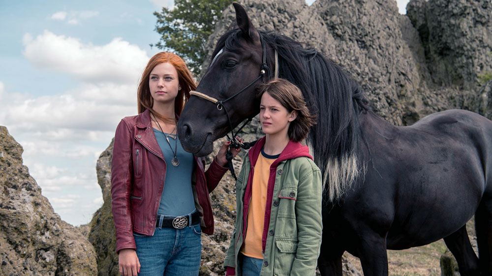 Szenenbild: Mika (links im Bild) und Ari (rechts im Bild) mit ihrem Pferd Ostwind, das zwischen den Mädchen steht.