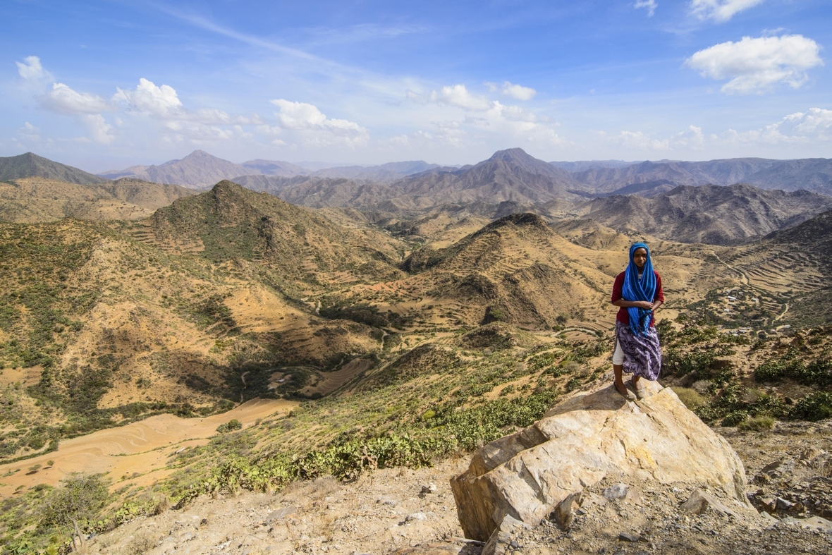 Eri­t­re­e­rin vor einer Berglandschaft in der Region Semienawi Kayih Bahri im Osten von Eritrea
