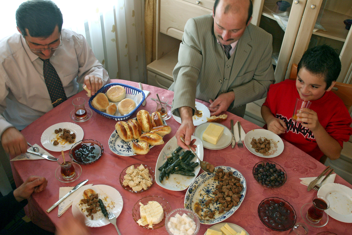 Am "Zuckerfest" am Ende des Ramadan verspeisen Familie Ötztürk und Imam Erdin Haseyin (Mitte) türkische Spezialitäten in Bayern.