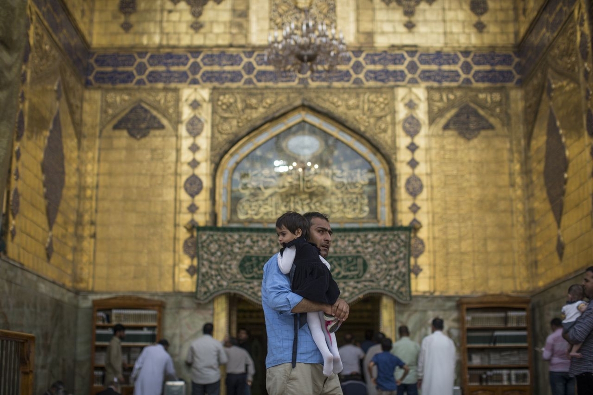 Ein schiitischer Mann trägt seine Tochter in der Imam-Ali-Moschee im Irak. Das ist eines der wichtigsten Heiligtümer der Schiiten.