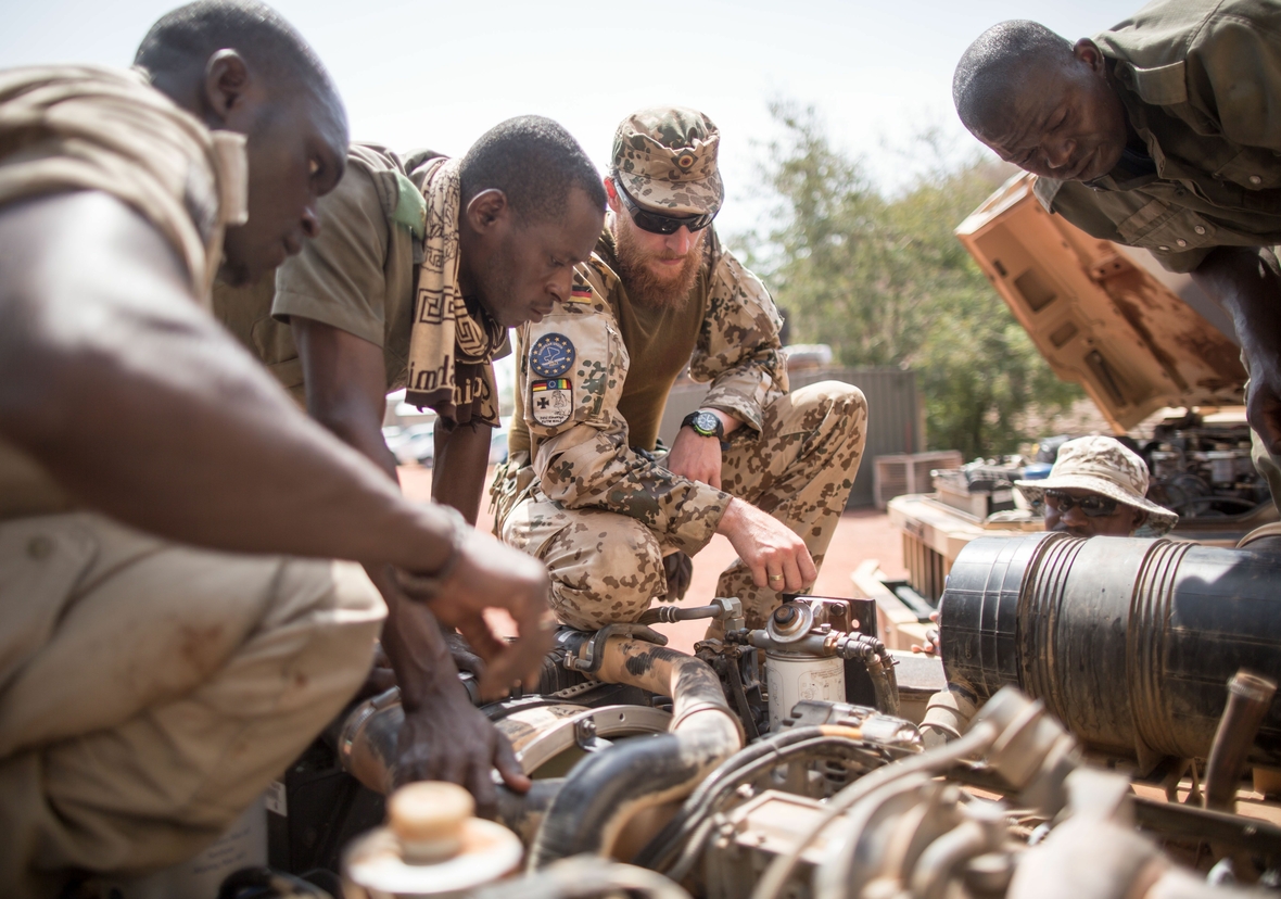Ein Soldat bildet Soldaten der Armee von Mali aus im Rahmen des Einsatzes der Vereinten Nationen. Die Soldaten schauen sich ein Fahrzeug an, das instand gehalten werden soll.