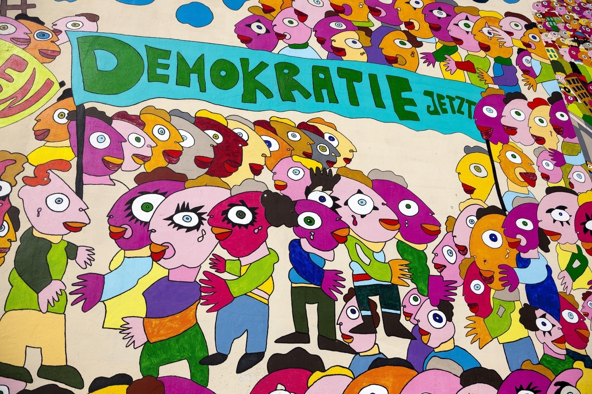 Bunte Zeichnung von Menschen mit dem Schriftzug "Demokratie jetzt" an einer Hauswand in Leipzig.