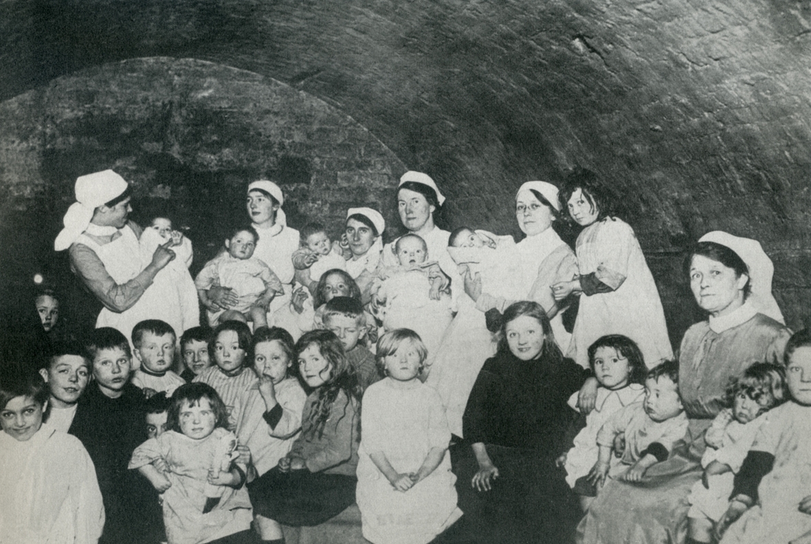 Kinder und ihre Betreuerinnen in Großbritannien suchen während des Ersten Weltkriegs Schutz in einem Bunker.