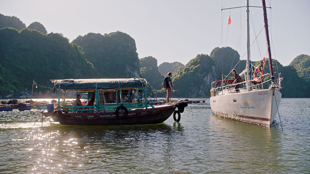 Szenenbild: Checker Tobi (links im Bild auf einem kleineren Boot) findet Marina (rechts) auf ihrem weißen Segelboot in der Halong-Bucht. 