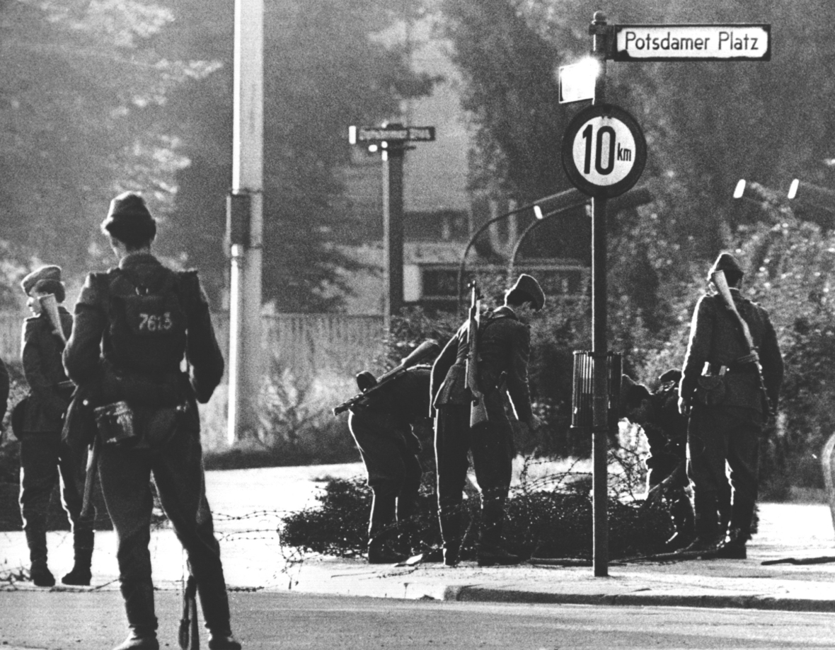 Volkspolizisten beim Errichten von Stacheldrahtsperren am Potsdamer Platz. Am frühen Sonntagmorgen des 13. August 1961 wurde unter der Aufsicht von bewaffneten Streitkräften der DDR mit der Errichtung von Straßensperren aus Stacheldraht und dem Bau einer Mauer begonnen, um den Ostteil Berlins vom Westteil abzusperren. Die Mauer sollte den ständig steigenden Flüchtlingsstrom von Ost- nach West-Berlin stoppen.