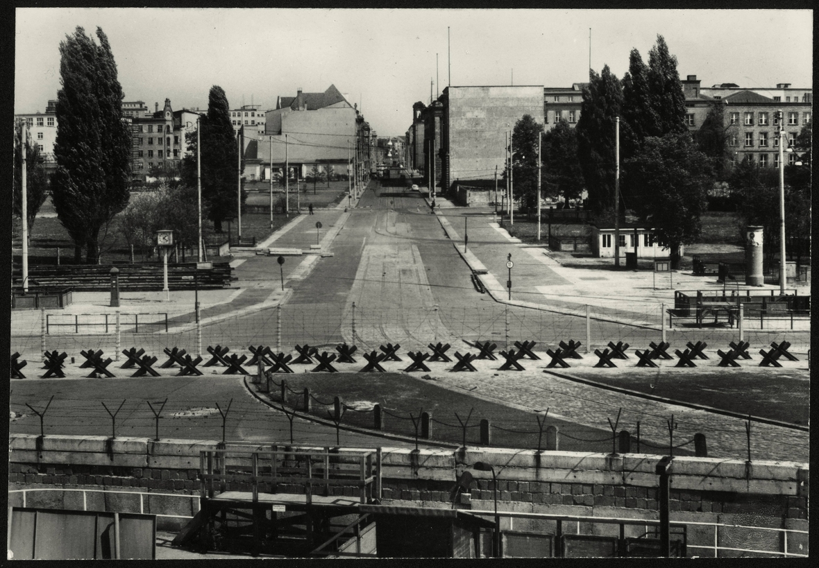 Die Foto-Postkarte aus der Zeit um 1963 zeigt im Vordergrund die Berliner Mauer. Zu sehen sind dahinter Panzersperren am Potsdamer Platz