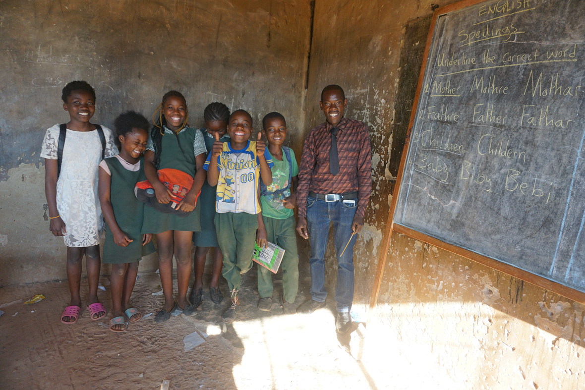 Schüler/innen und Lehrer einer öffentlichen Schule in Sambia. Die Schule ist nicht gut ausgestattet.