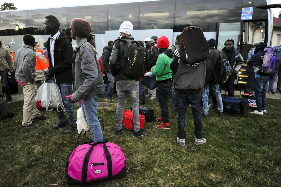 Unbegleitete junge Flüchtlinge in Frankreich im Herbst 2016. Sie tragen Rucksäcke und stehen auf einer Wiese.
