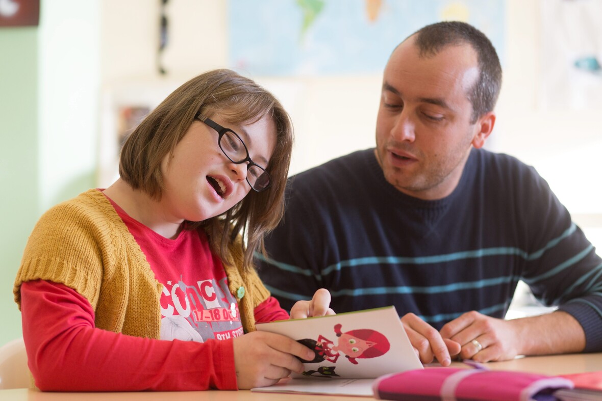 Mädchen mit Down-Syndrom in der Schule mit Schulhelfer.