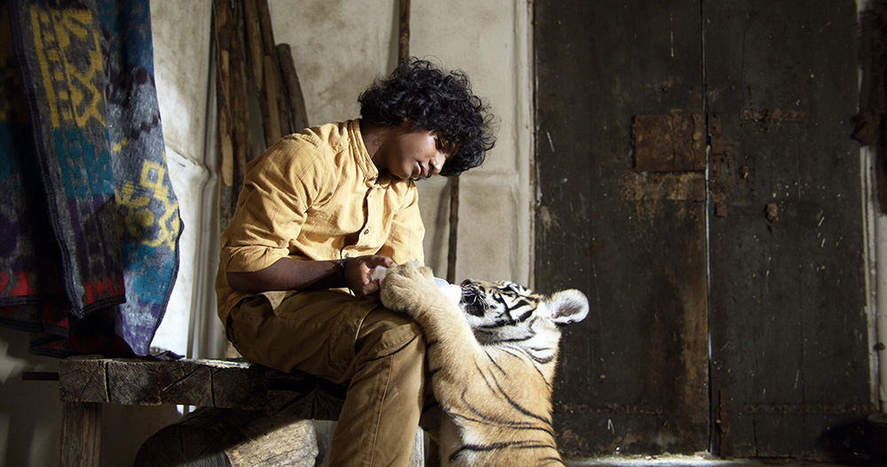 Szenenbild: Der Junge Balmani (links im Bild) füttert das Tigerbaby (rechts im Bild) mit Milch.