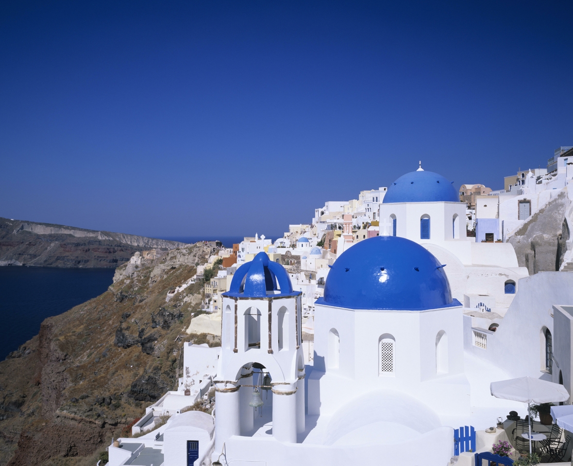 Eine weiße Kirche mit blauen Kuppeln in der Stadt Oia auf der griechischen Kykladeninsel Santorini.