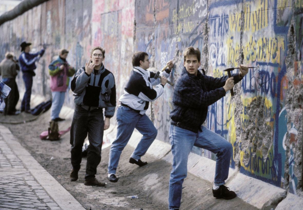 Junge "Mauerspechte" schlagen im Dezember 1989 Steine aus der Berliner Mauer. Sie hauen mit Hammer und Meißel Steine aus einem Mauerteil.