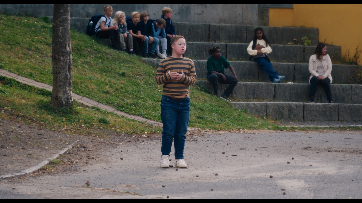 Lars steht einsam auf dem Schulhof, während die anderen Kinder ihn meiden.