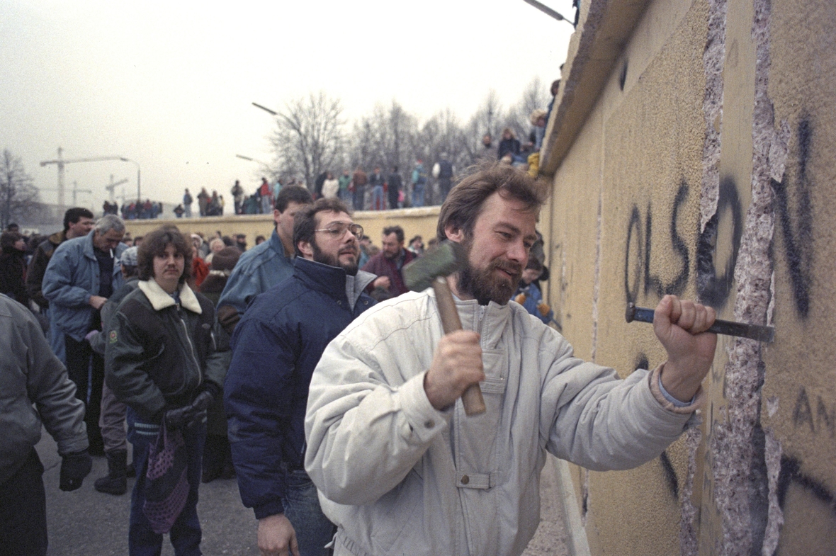 1. Januar 1990 in Berlin: Berlinern klettern und laufen auf der Berliner Mauer. Souvenirjäger, sogenannte Mauerspechte, hämmern Stücke aus der Berliner Mauer.