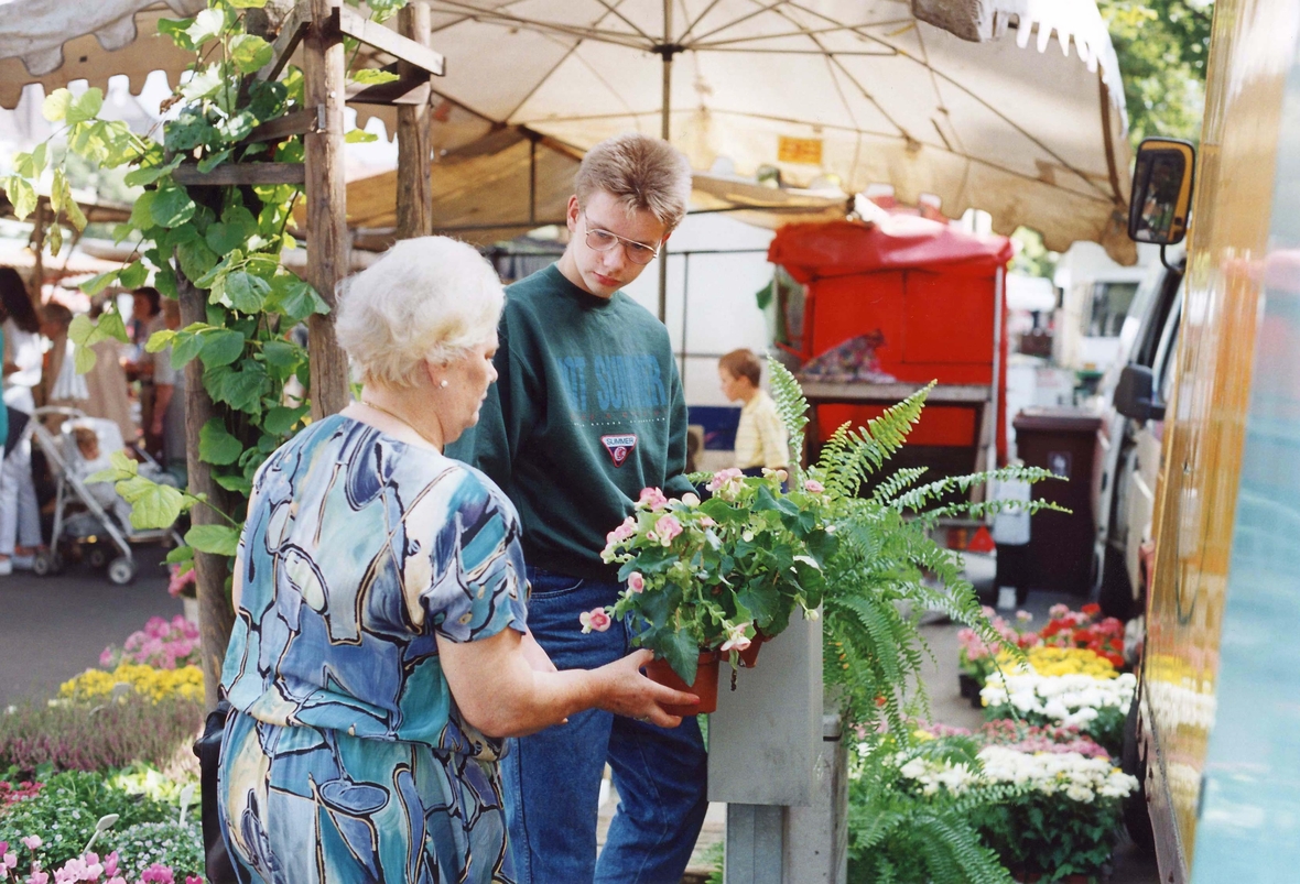 Ein junger Mann zeigt einer älteren Dame Blumen. 