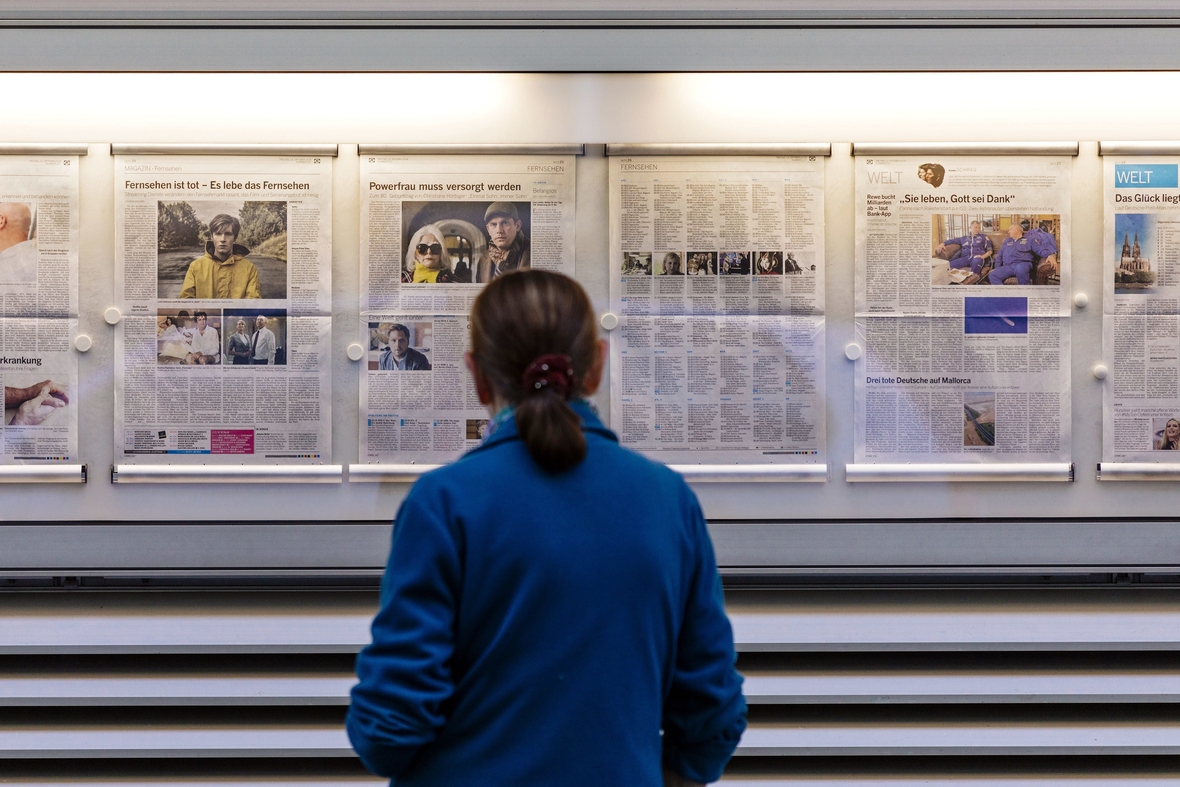 Eine Passantin betrachtet die aktuelle Ausgabe einer Zeitung.