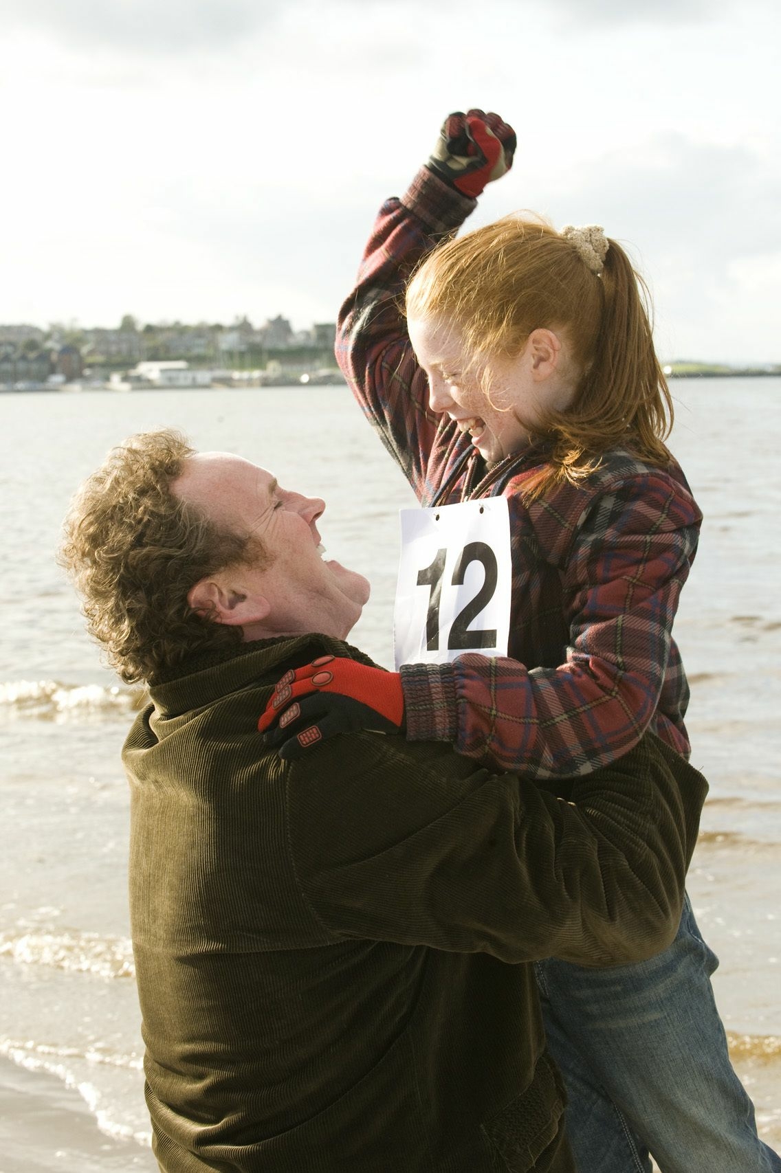 Szenenbild: Marys Vater hebt das Mädchen in Luft. Beide lachen und freuen sich über Marys Sieg beim Rennen.