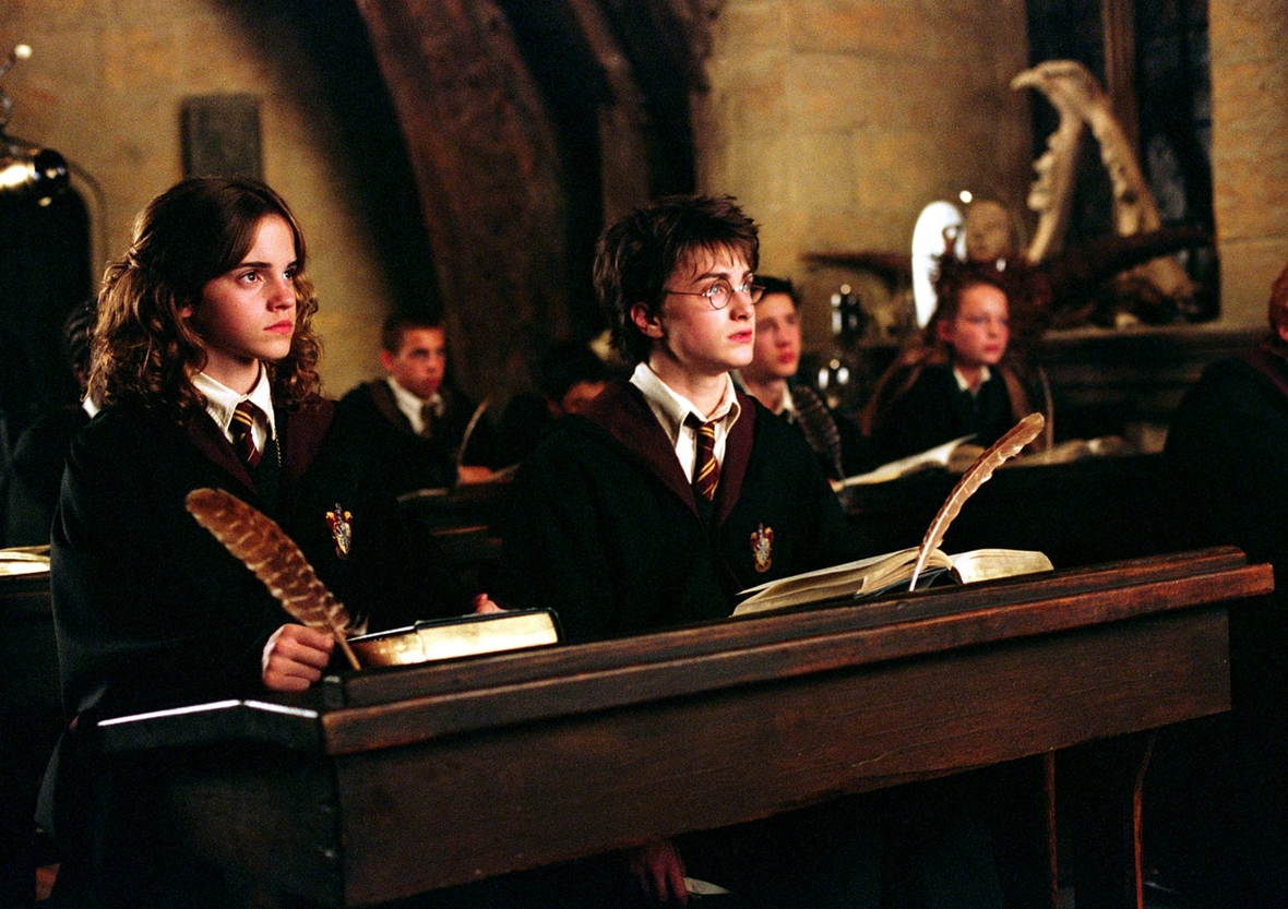 Szenenbild: Hermine, links, und Harry, rechts, sitzen an der Schulbank