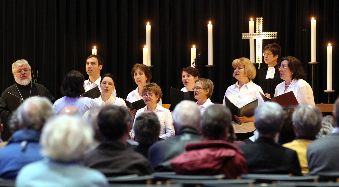 Ein Kirchenchor singt während eines Gottesdienstes in Berlin. Die Zuhörer/innen lauschen in den Kirchenbänken.