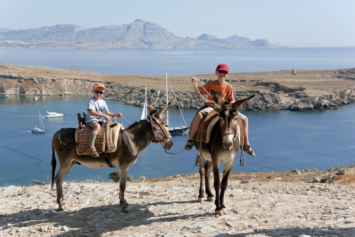 Zwei Kinder reiten im Urlaub auf der Insel Rhodos auf Eseln.