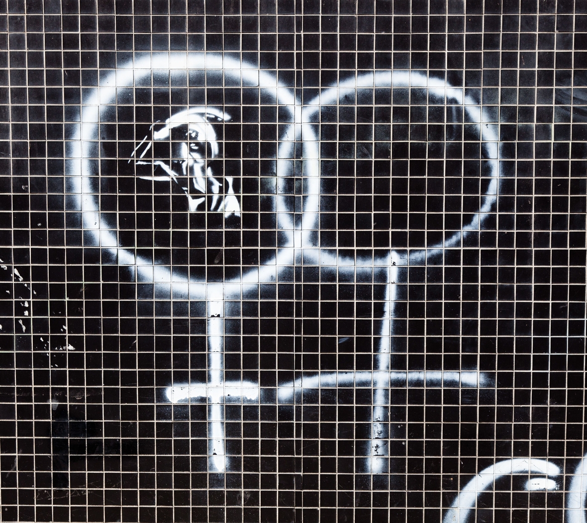 Zwei Symbole für 'weiblich' sind auf eine Kachelwand gesprüht. Sie werden von der Frauenbewegung als Erkennungszeichen verwendet.