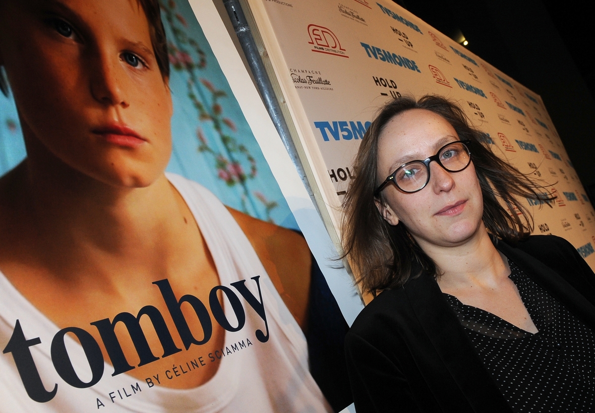 Die Regisseurin Celine Sciamma mit Brille und langen Haaren bei der Premierenfeier ihres Films vor dem Filmplakat