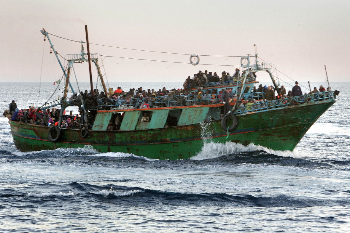 Ein Flüchtlingsboot auf dem Meer. Es ist überfüllt mit Menschen, die aus ihrer Heimat fliehen.