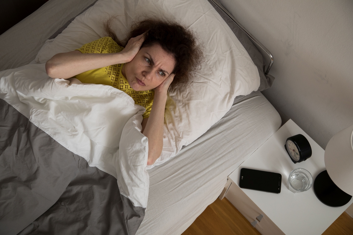 Eine Frau hält sich in einer Wohnung die Ohren zu