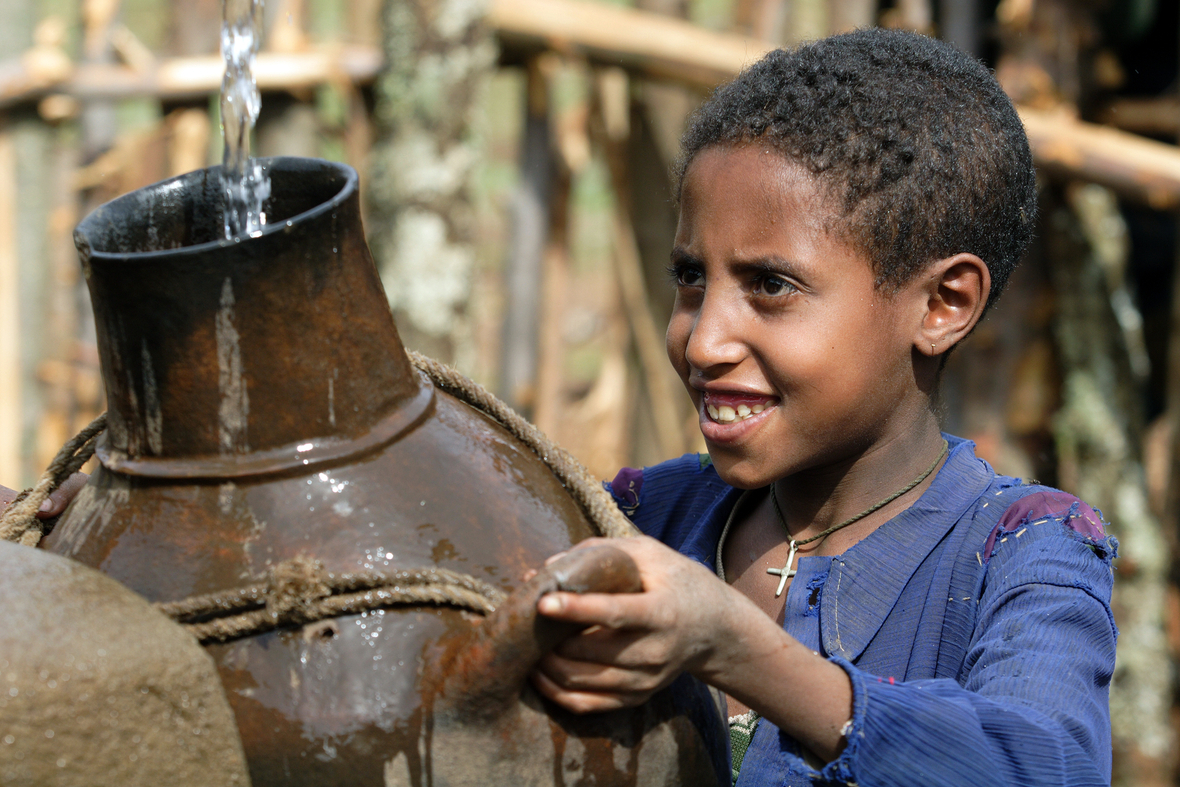 Ein Mädchen füllt an einer Pumpstation in Äthiopien Wasser in ihren Tonkrug.