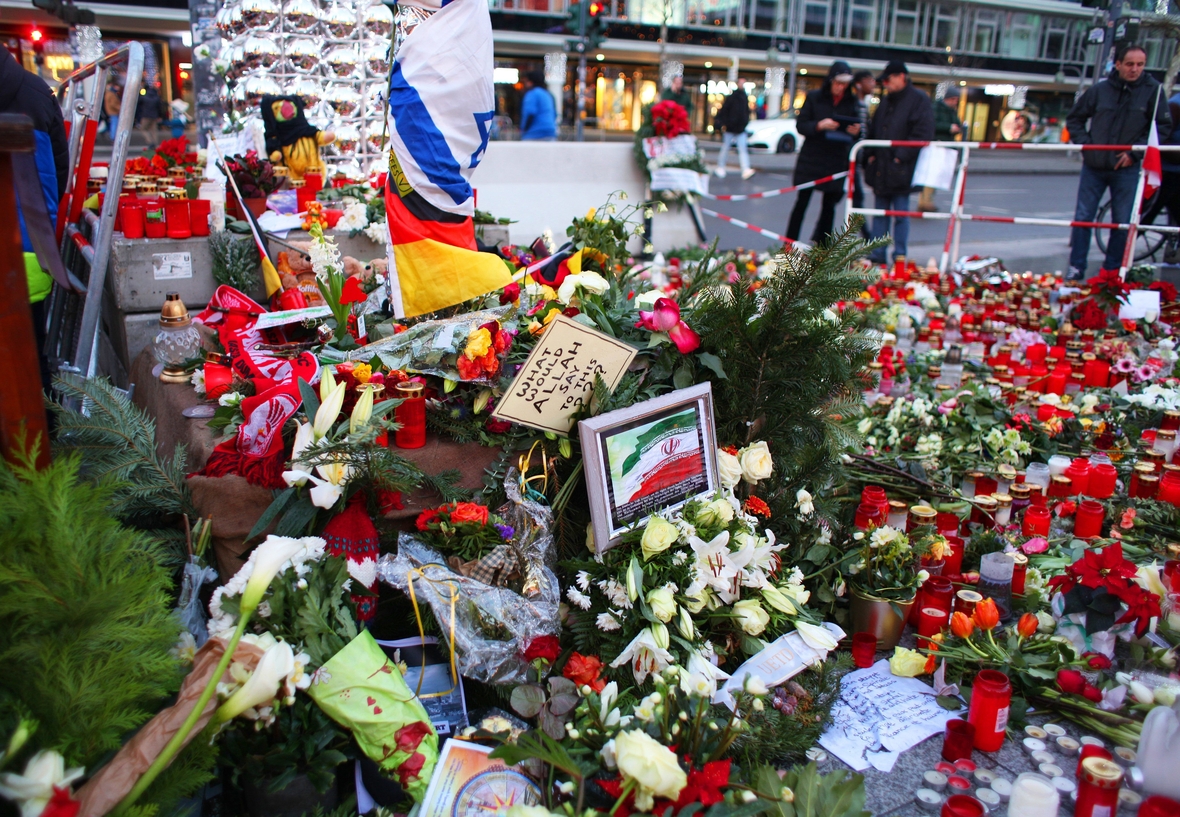 Gedenken an die Opfer des islamistischen Anschlags beim Weihnachtsmarkt 2016 in Berlin. Viele Blumen sind mit Botschaften des Erinnerns versehen. Eine Aufschrift lautet: Was würde wohl Allah dazu sagen?
