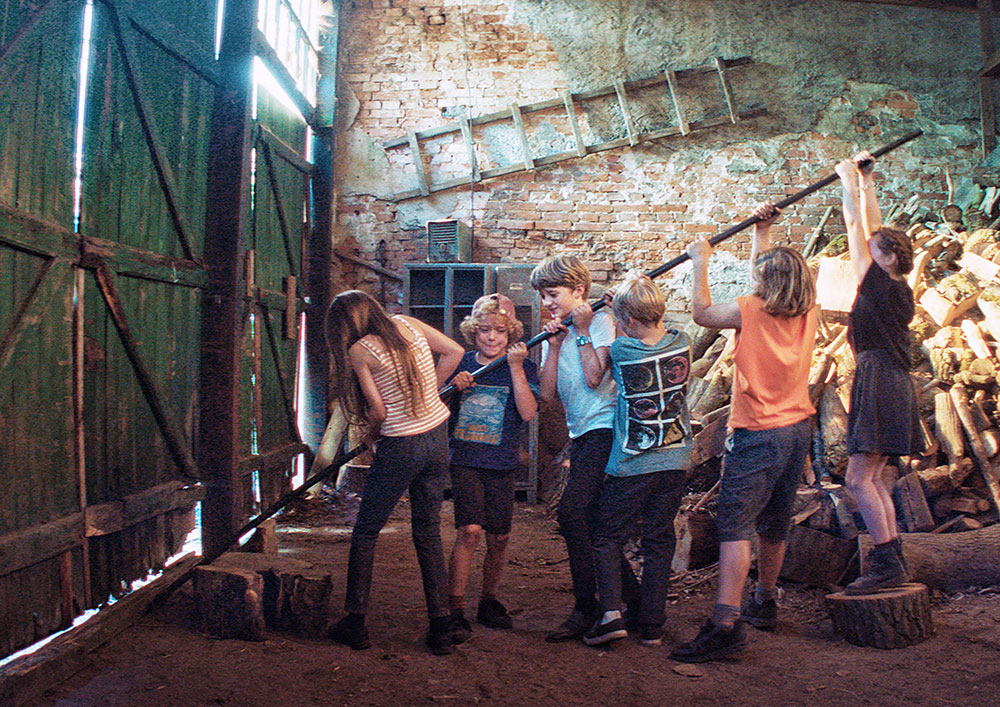 Szenenbild: Die Kinder sind in einer Scheune eingesperrt. Aber sie wissen sich zu helfen und hebeln mit einer langen Stange das Tor auf.