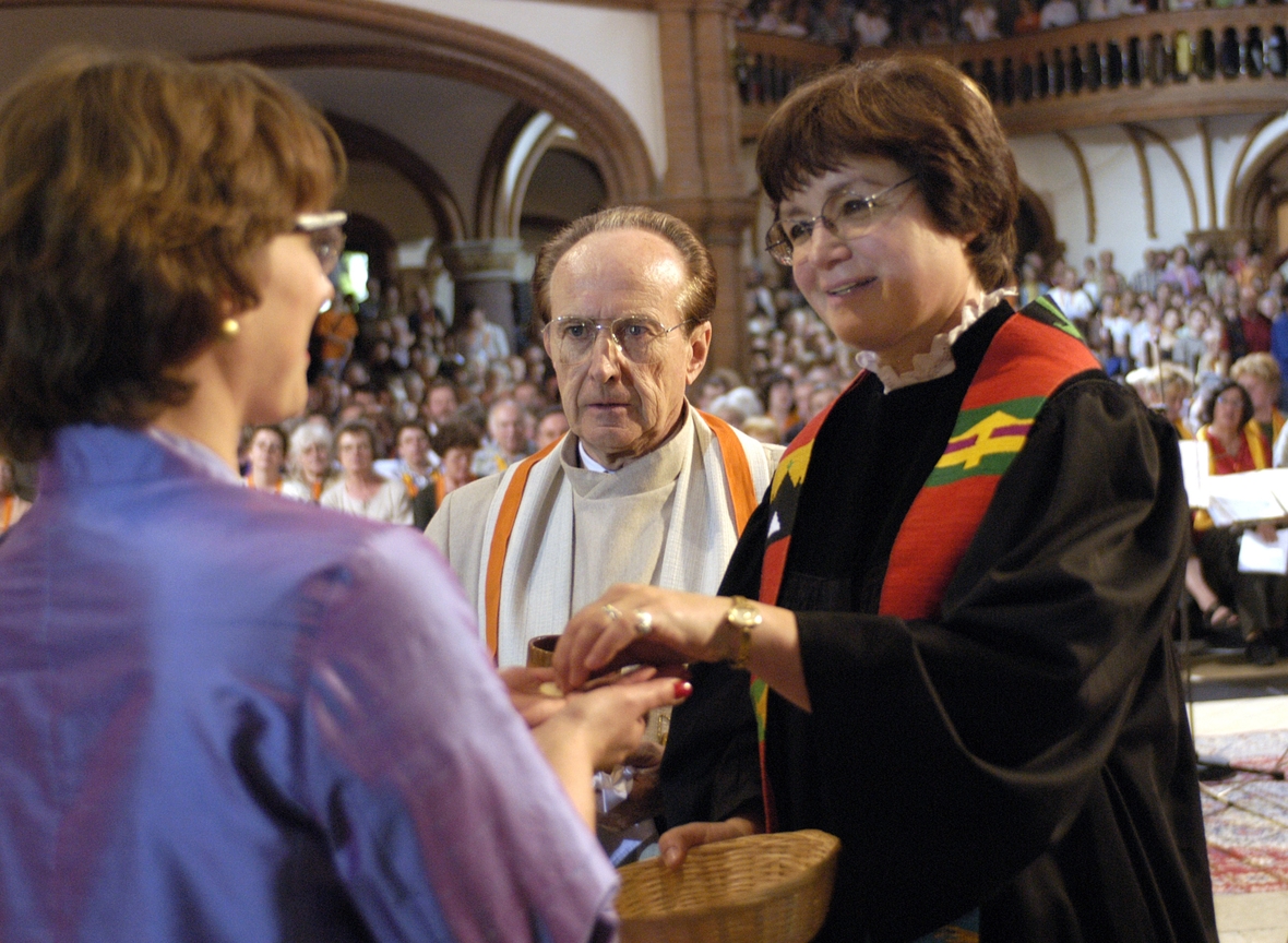 Ein katholischer Priester teilt mit einer evangelischen Hochschulpfarrerin bei einem ökumenischen Gottesdienst die Kommunion aus. 