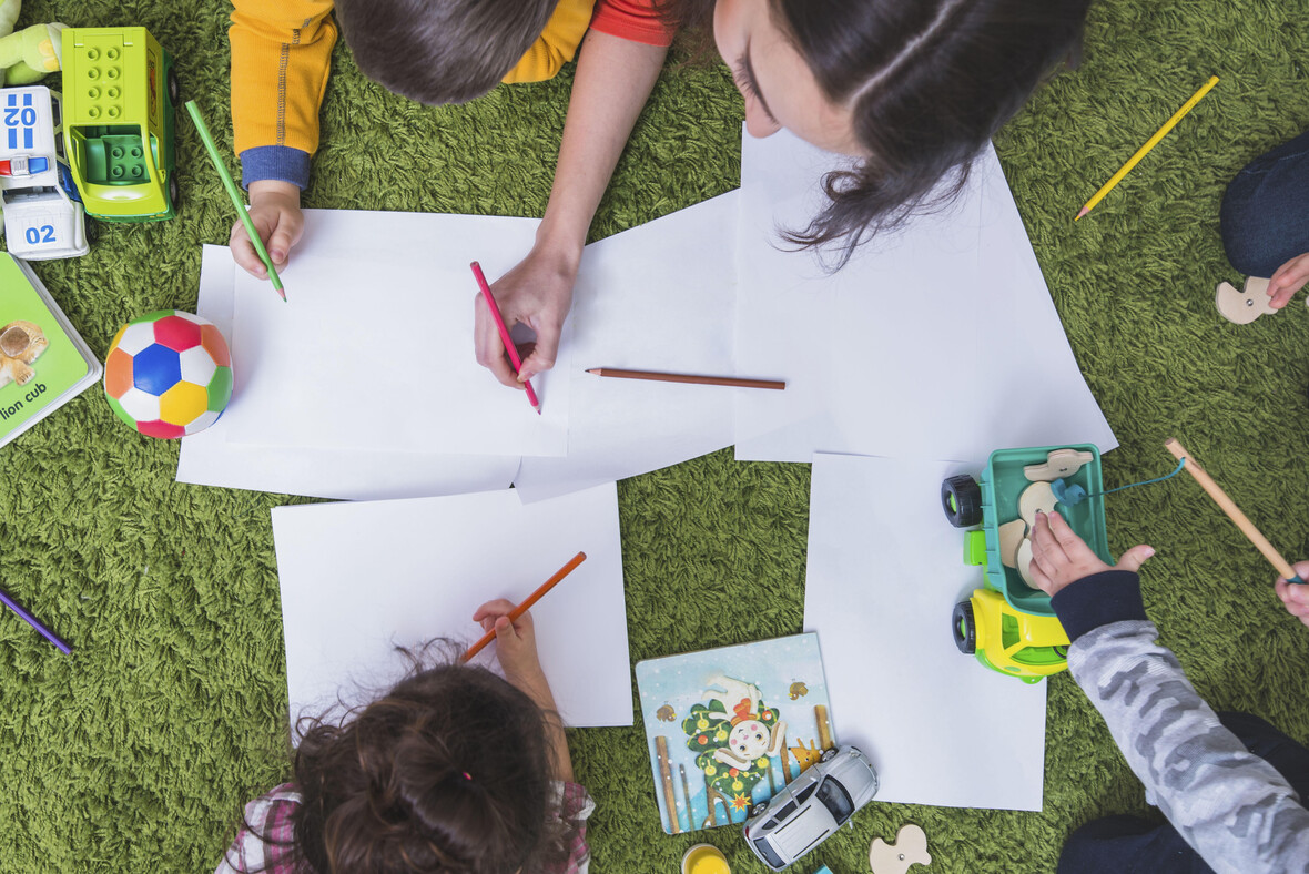 Kinder malen mit bunten Stiften.
